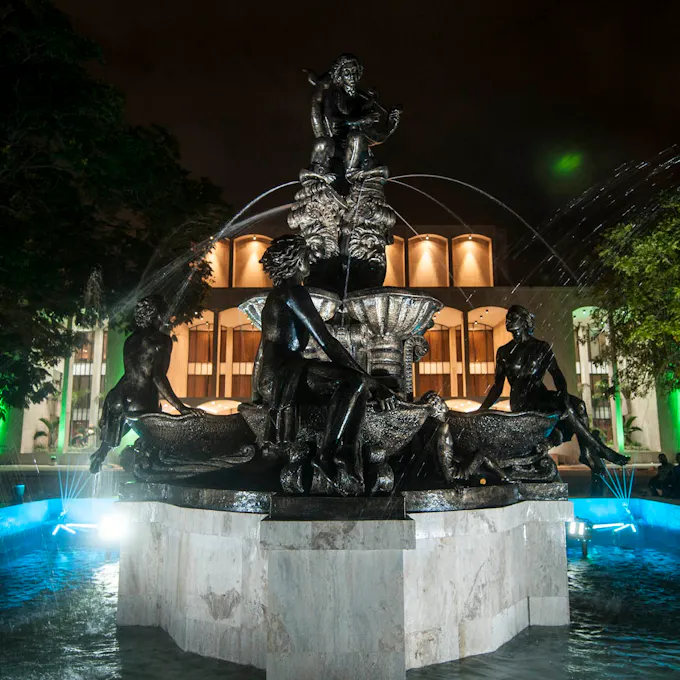 A water fountain of nymphs and seashells in front of a brightly lit auditorium