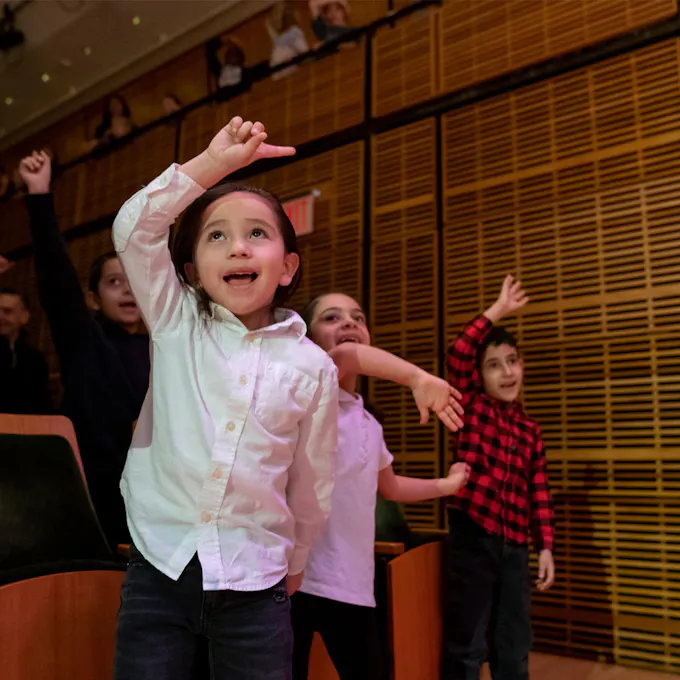 Children wave their hands during a concert in Zankel Hall