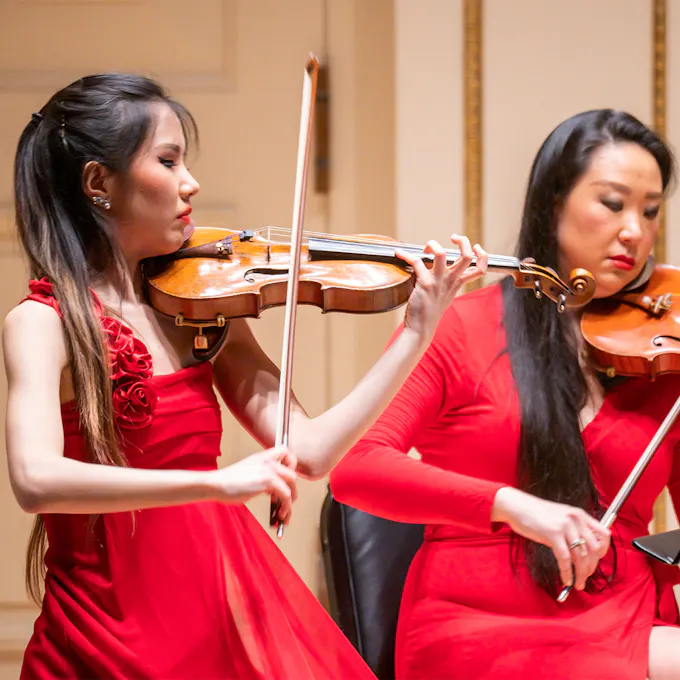 Two violinists performing on stage
