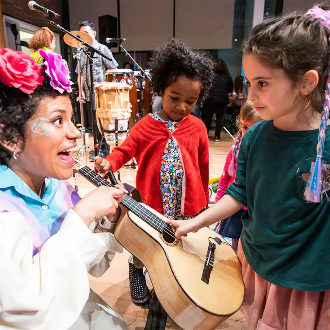A musician showing a guitar to young children