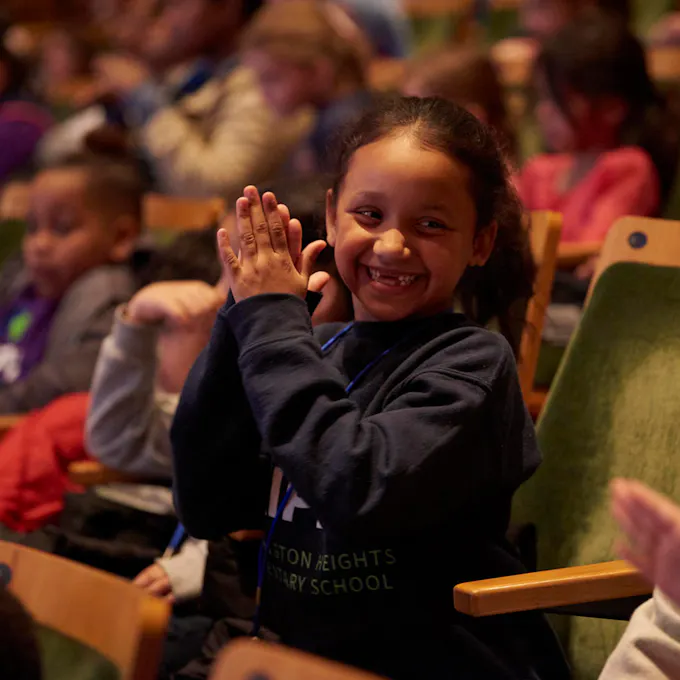 A young girl claps and smiles