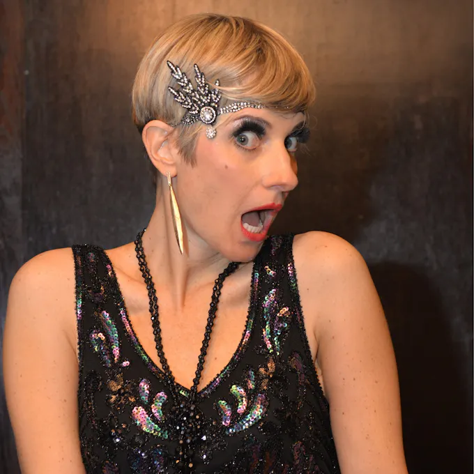 A woman wearing a black flapper gown and silver jewelled headband