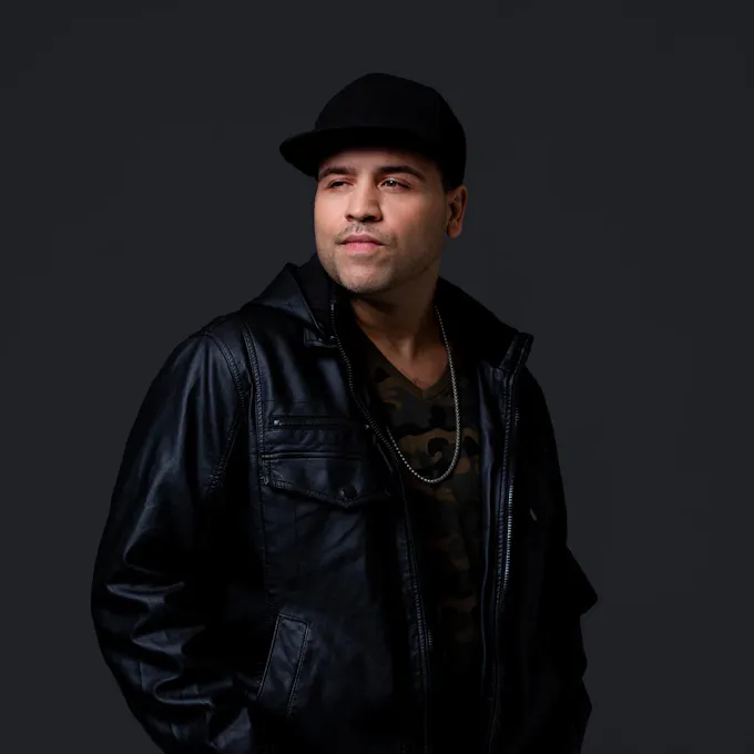 Don Sonero wearing a black leather jacket and black cap