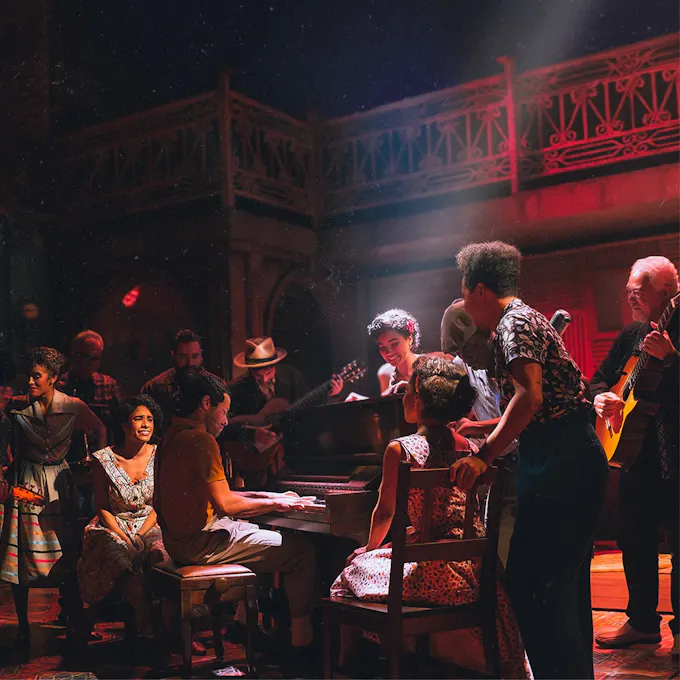 Actors gathered around a piano playing music together