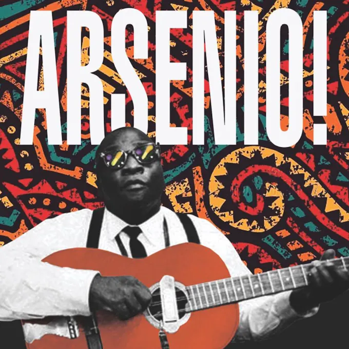 A man wearing sunglasses plays guitar against a colorful backdrop