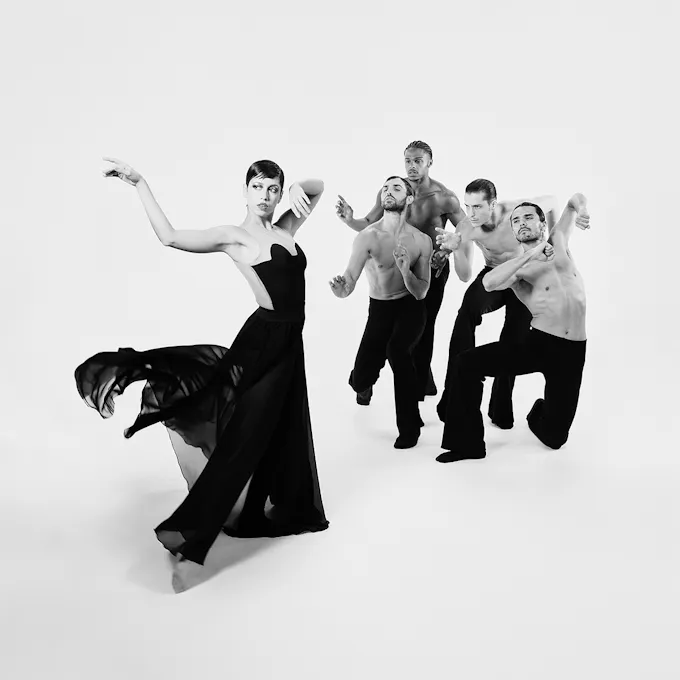 A dancer in the foreground with four dancers in the background positioned toward the primary dancer