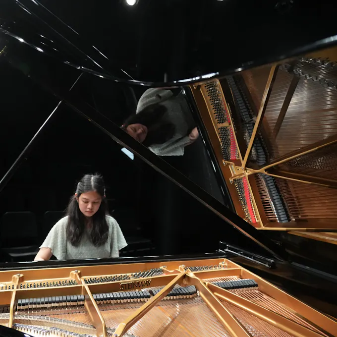 A young woman plays piano on stage