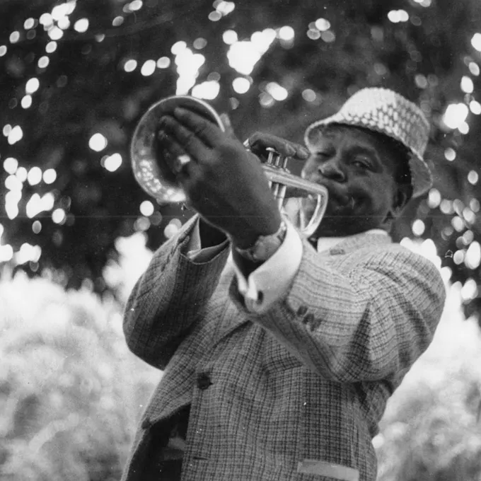 A man wearing a straw hat plays trumpet