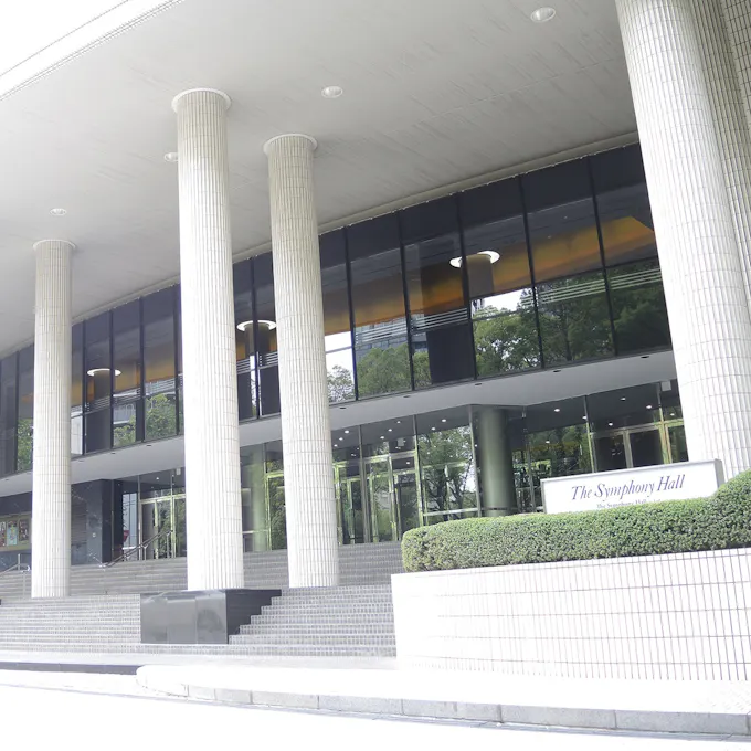 A symphony hall with tall white columns and a glass facade