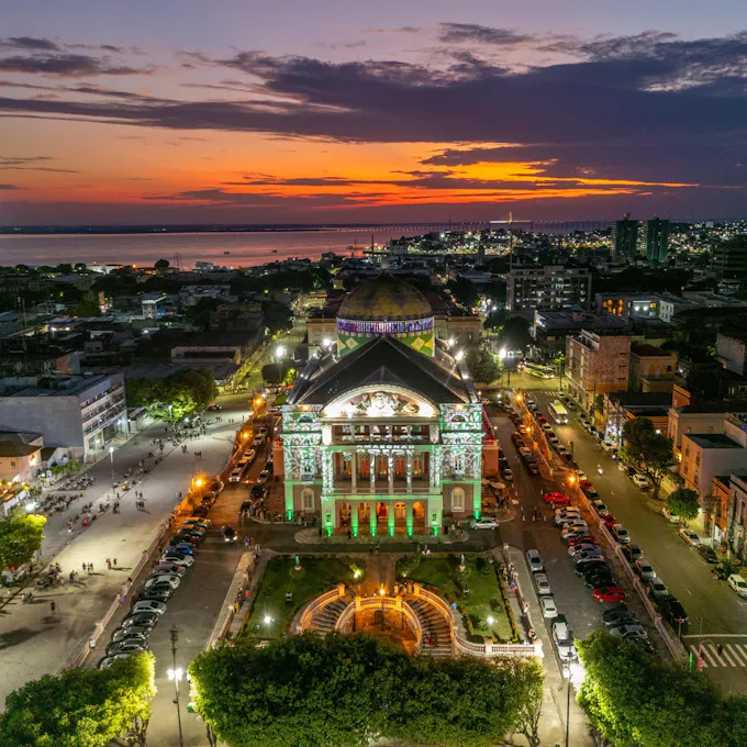 Overhead view of a columned lighted concert hall in the center of a town square