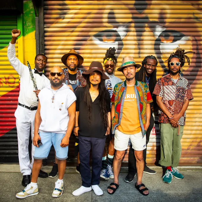 Members of the Brown Rice Family pose before a warehouse door painted with the image of a tiger