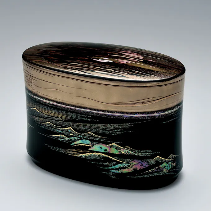 A decorative gold-topped oval-shaped box painted with ocean waves