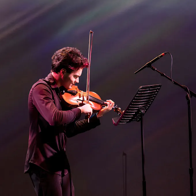 A young man plays violin on stage