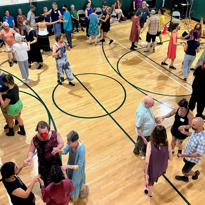 People dance in groups of four on a gym floor