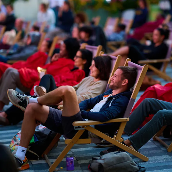 Smiling men and women lounge outdoors in deck chairs