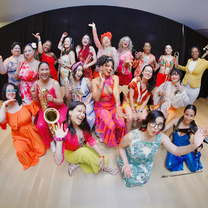 A group of musicians standing and kneeling, wearing colorful clothing and posing with their instruments