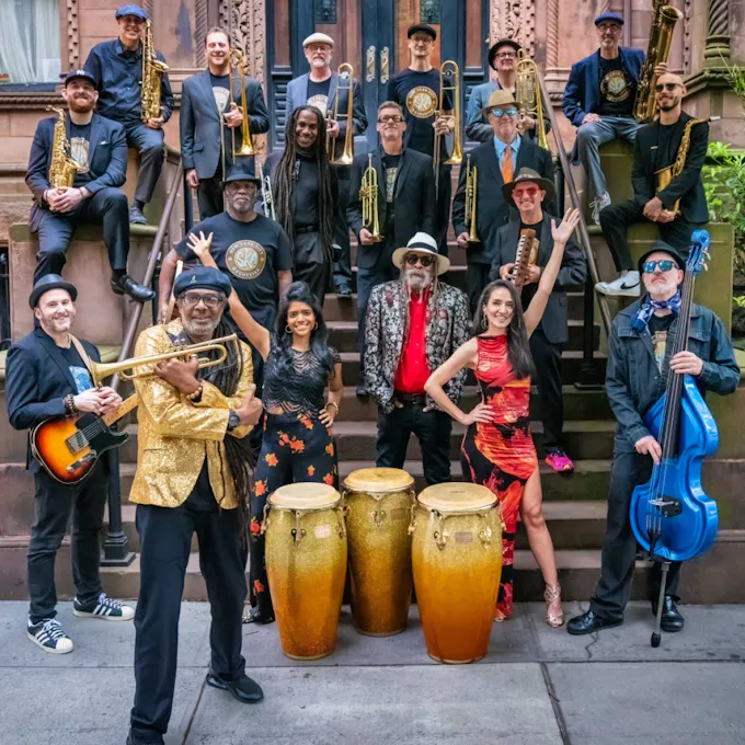 Musicians of NYC Ska Orchestra pose together with their instruments on the stoop of an apartment building