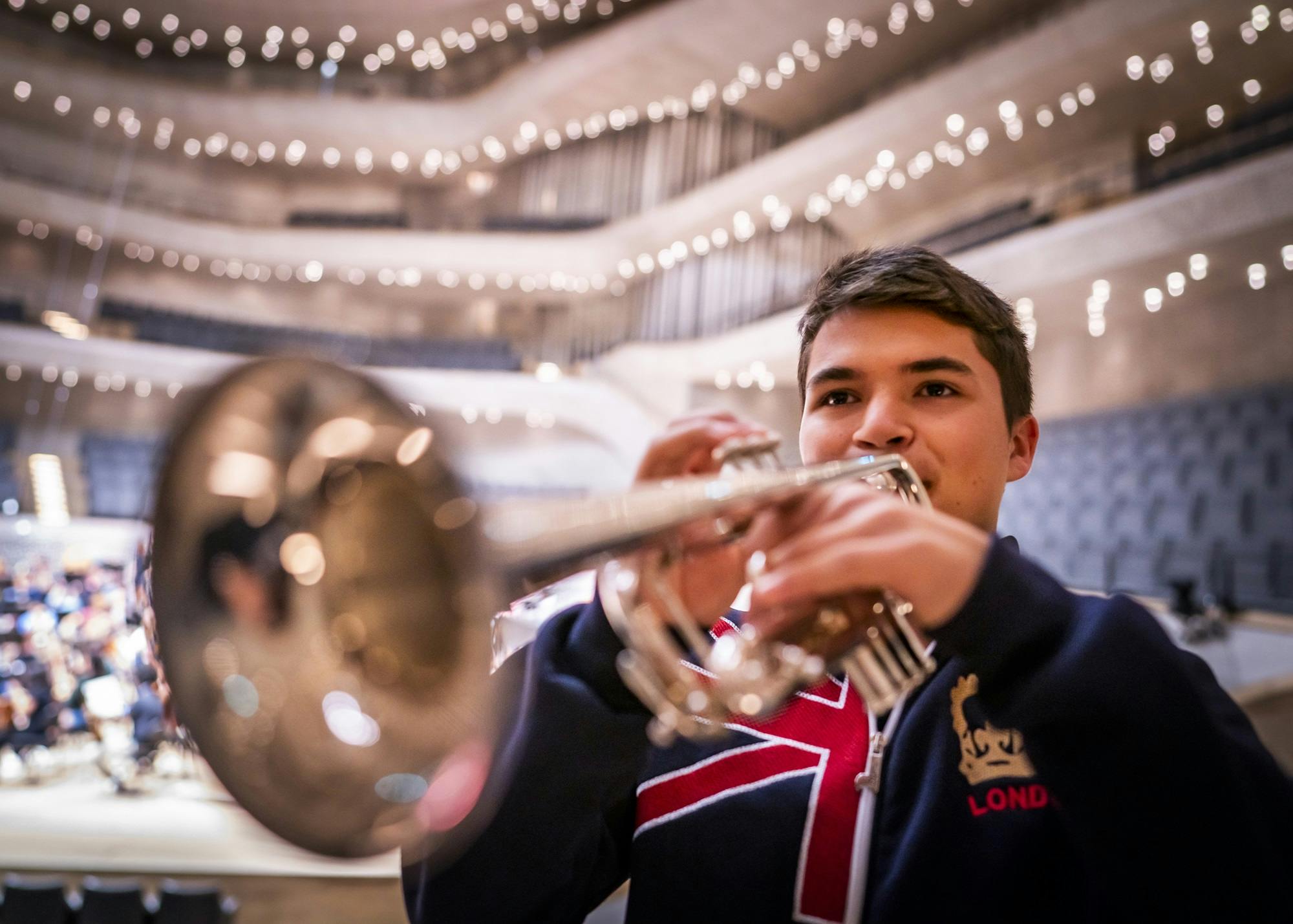 Gabriel Ortiz holding his trumpet in front of the stage of the Elbphilharmonie Hamburg.