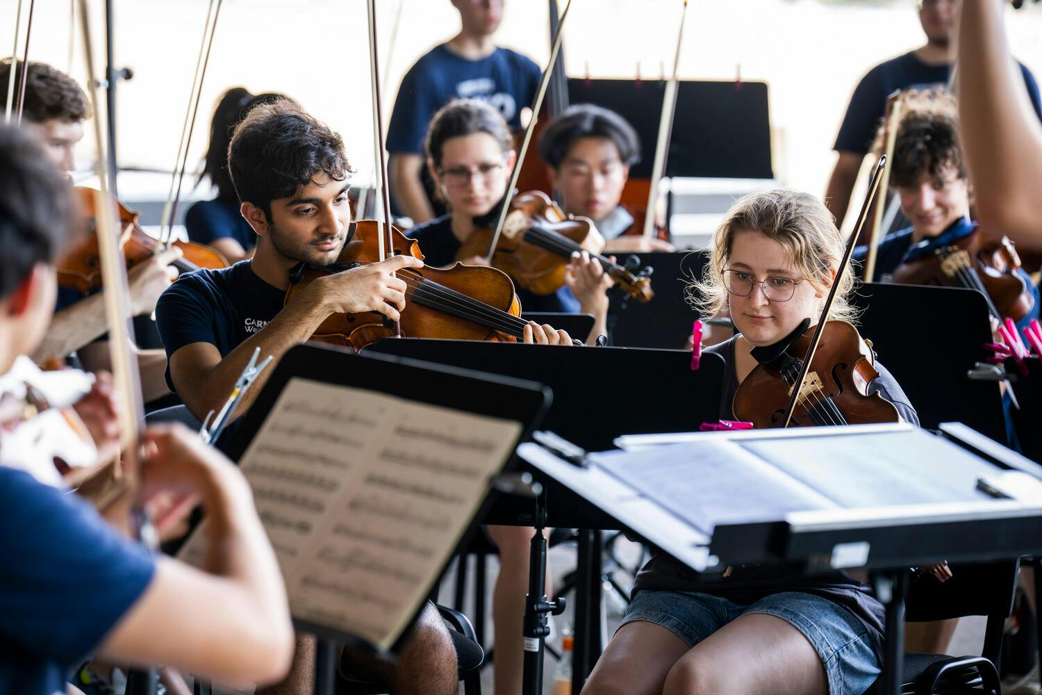 Young NYO-USA violinists rehearse before music stands