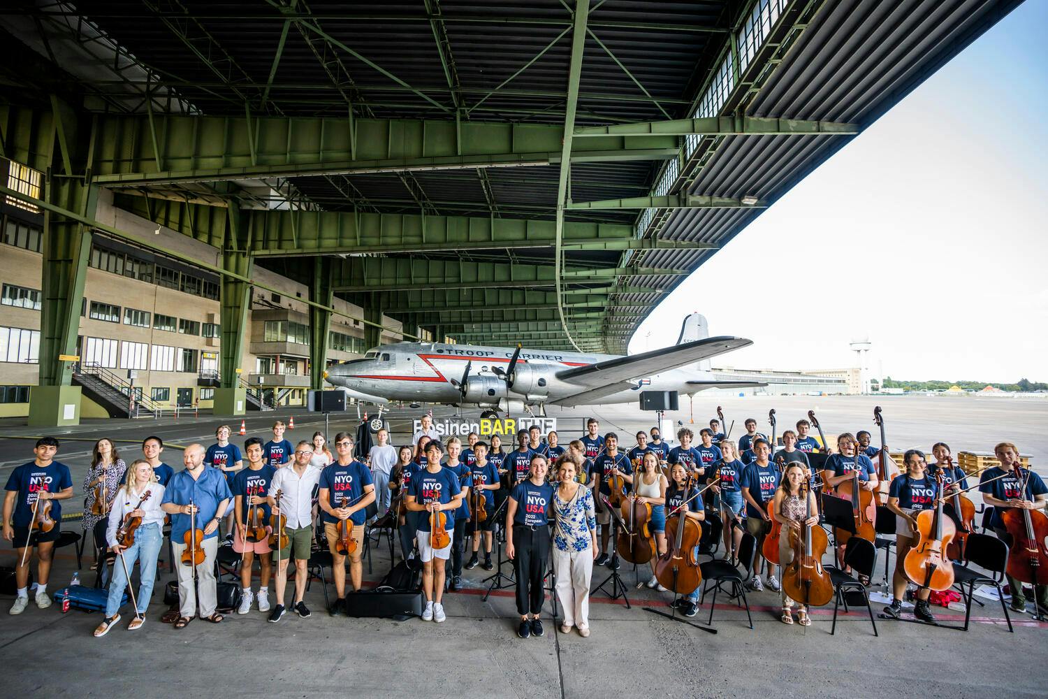 Group photo of NYO-USA and Ukrainian musicians in airplane hangar