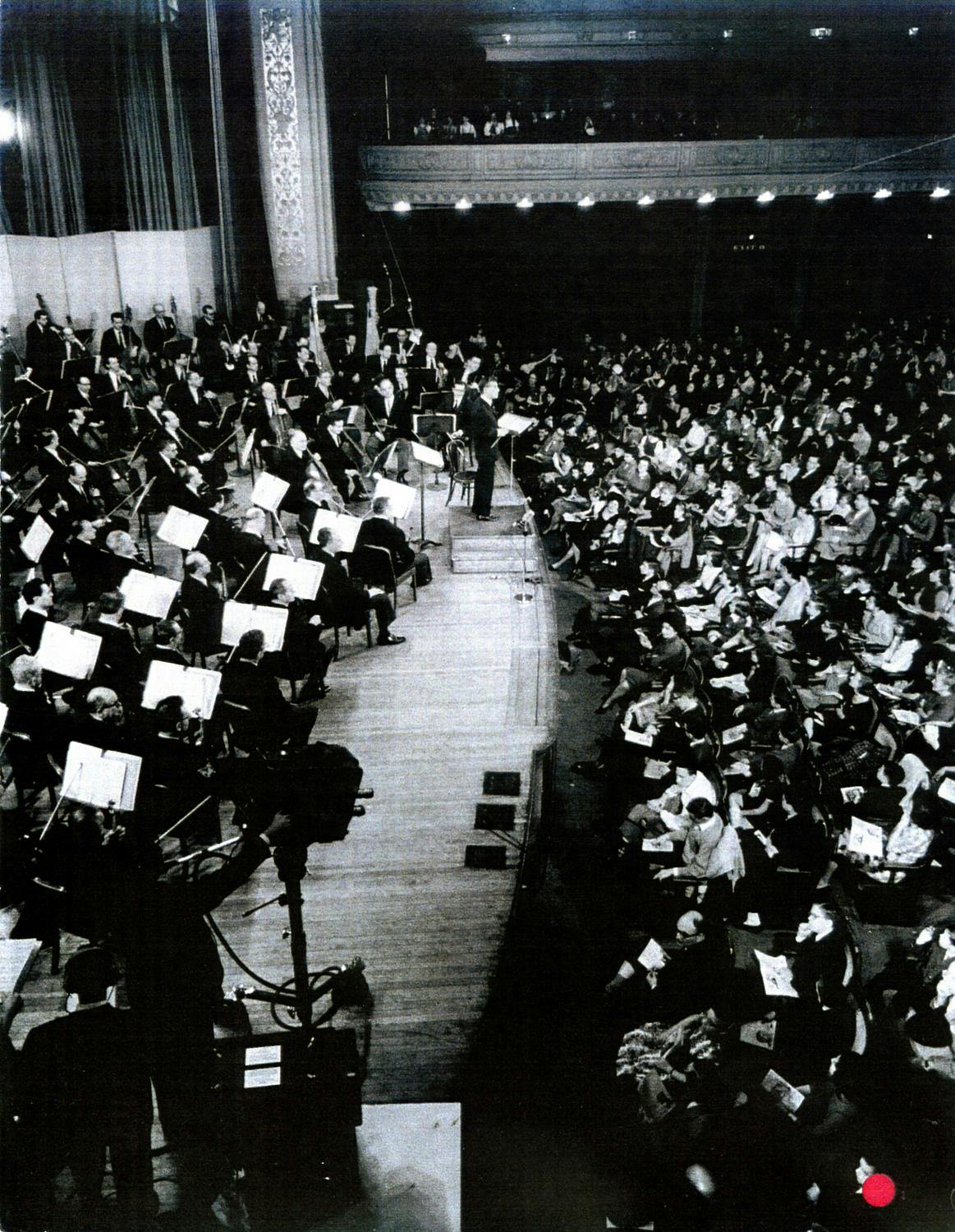 Leonard Bernstein on stage conducting an orchestra before an audience
