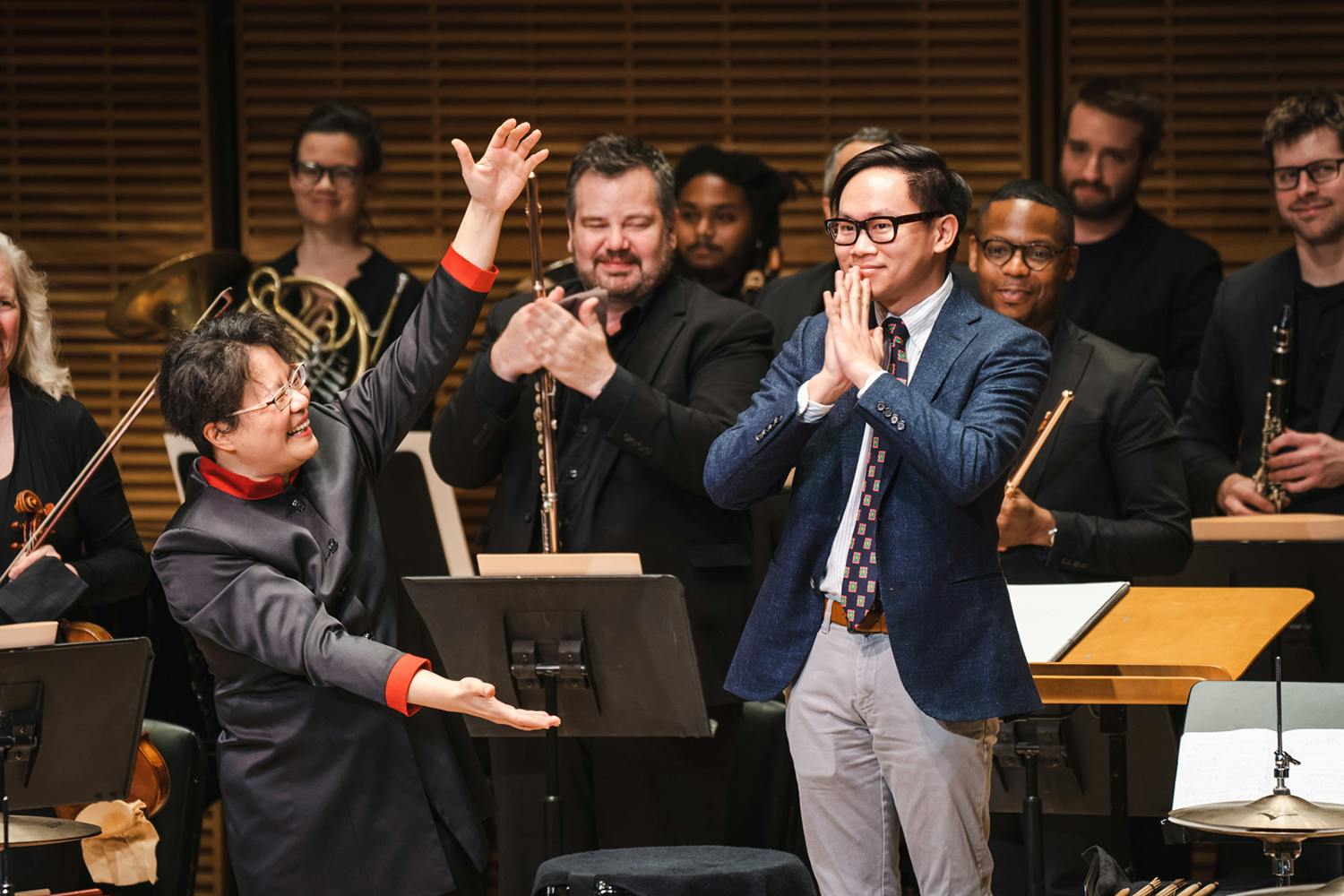 A smiling Mei-Ann Chen holds her arms out wide to Viet Cuong, on stage before the orchestra