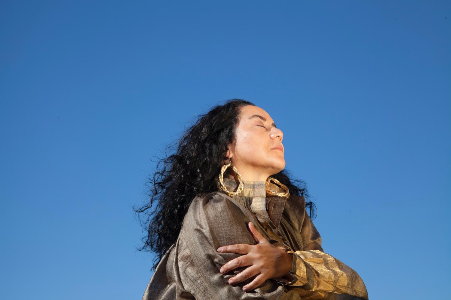 Claudia Acuña with her arms wrapped around her body.