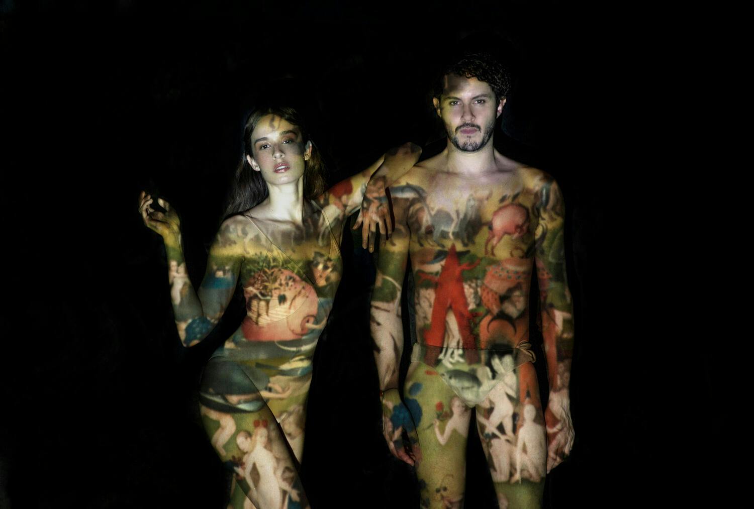 Monsieur Periné duo standing together with a painting projected onto their bodies.
