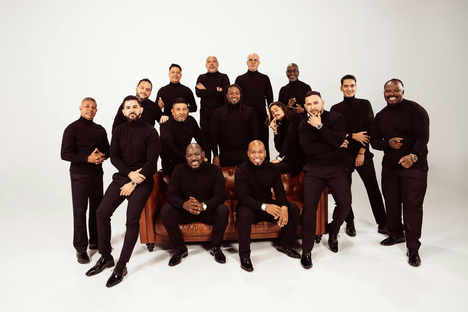 Members of Grupo Niche sitting and standing around a couch