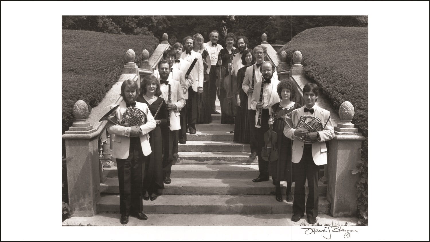 Members of the Orchestra of St Luke’s standing on outdoor stairs with their instruments