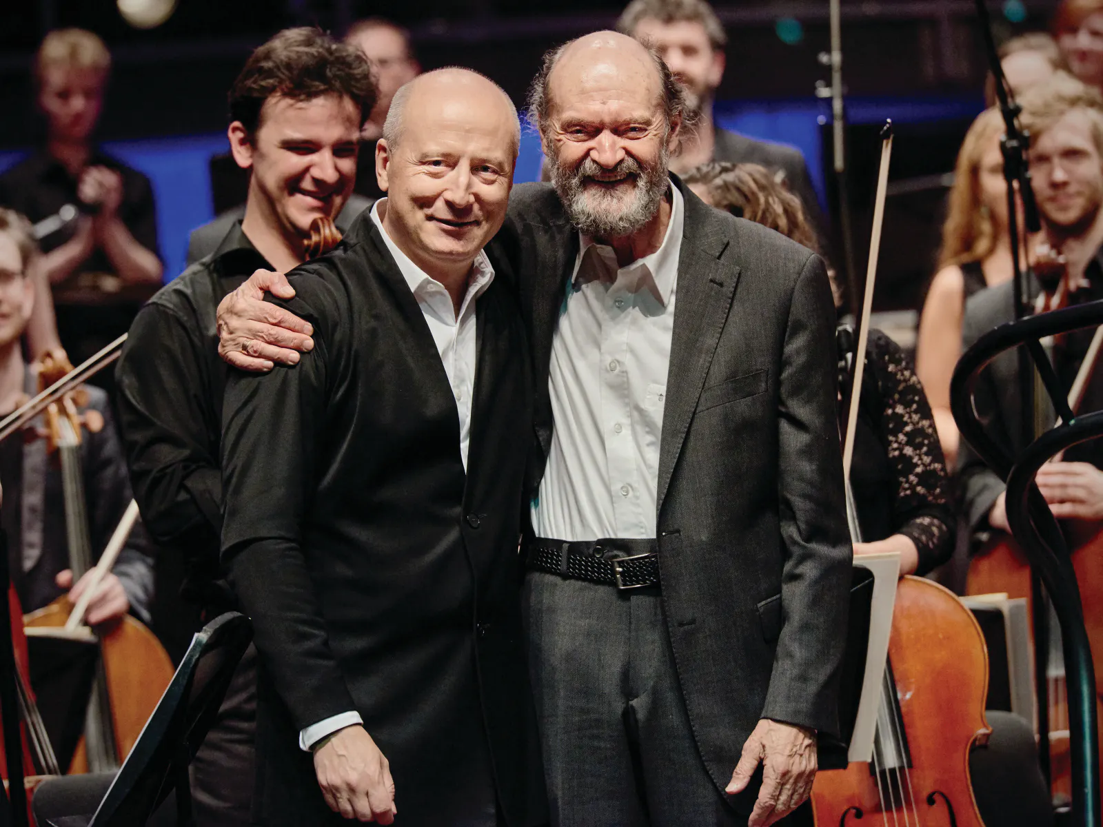 Paavo Järvi and Arvo Pärt standing next to each other with the Estonian Festival Orchestra behind them.