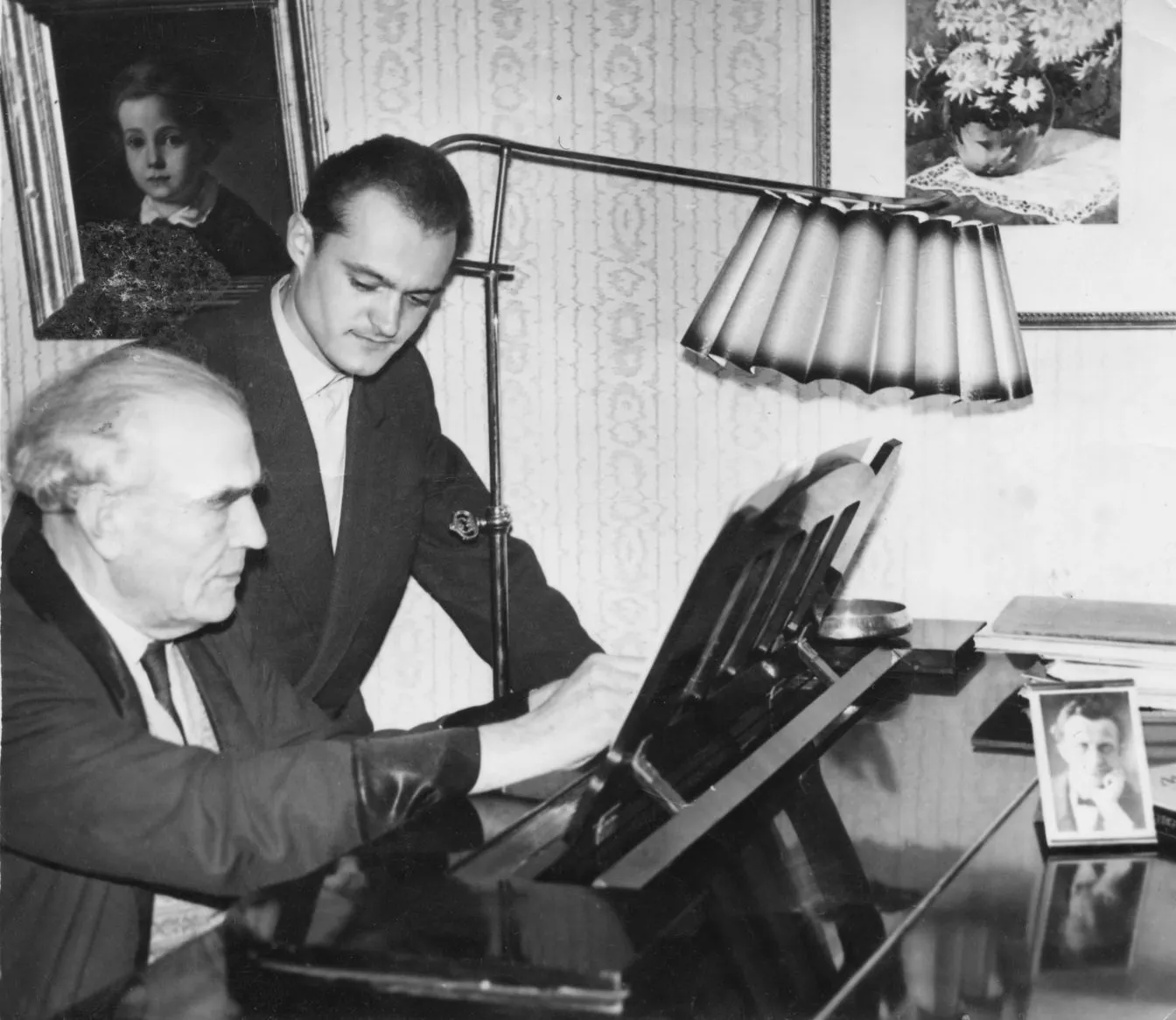 Heino Eller sitting at a piano while Arvo Pärt stands beside him at the Tallinn State Conservatoire.