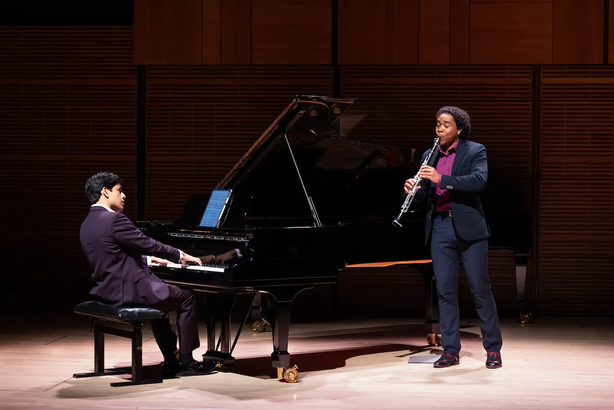 A student playing the clarinet, accompanied by a pianist on stage in Zankel Hall.