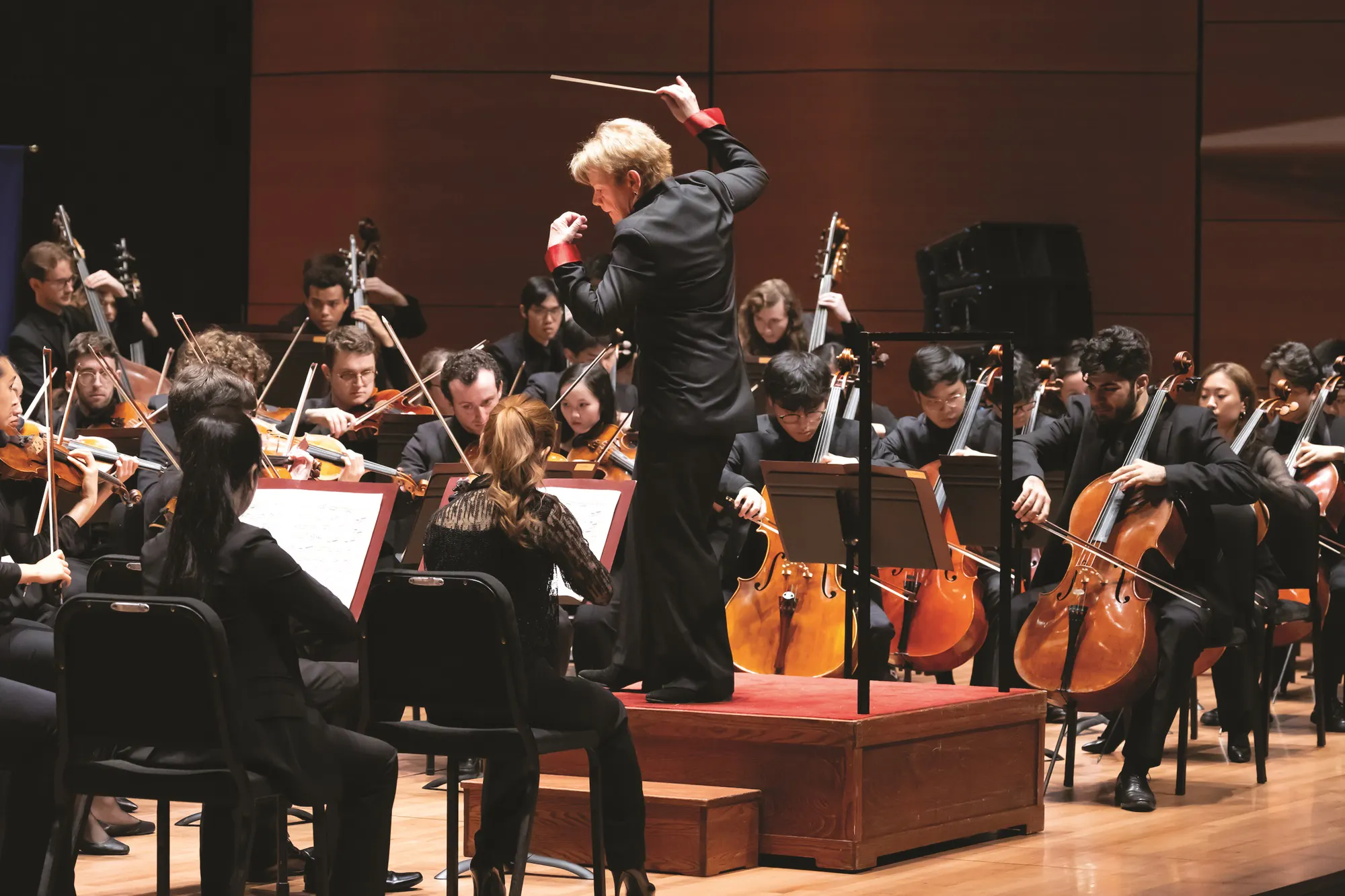 Marin Alsop conducting the Juilliard Orchestra on stage.