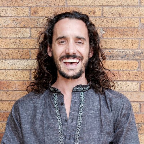 A man standing against a brick wall.