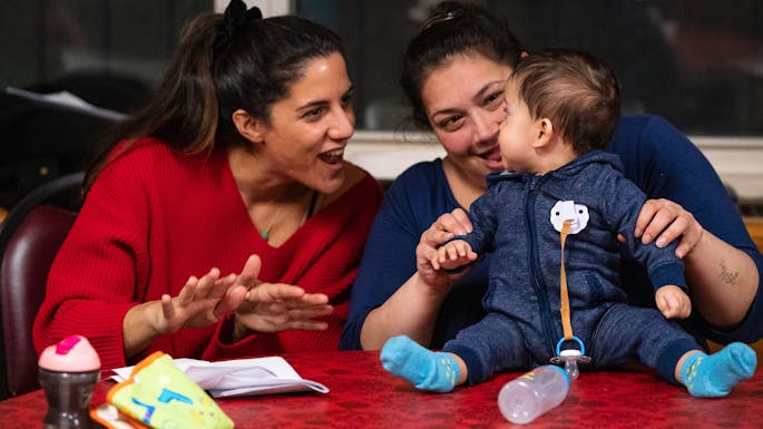 Two mothers sing to their baby