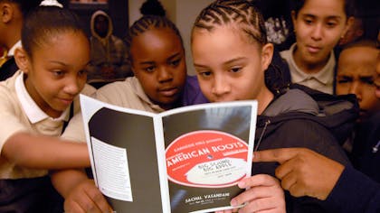 Young students peruse the Carnegie Hall book "American Roots" together
