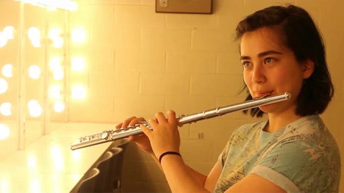 A young female musician plays the flute