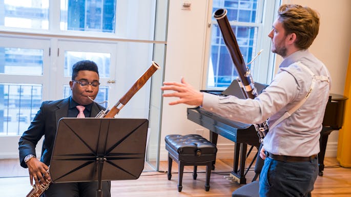 A teacher instructs a young musician