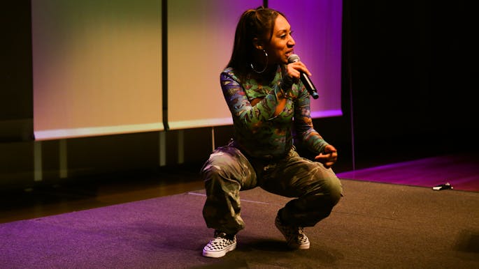 Queen Jo, a female MC in a patterned outfit, performs in the Black Thought master class showcase.