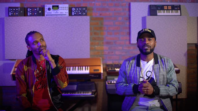 Chen Lo and Asante Amin sit before a bank of keyboards
