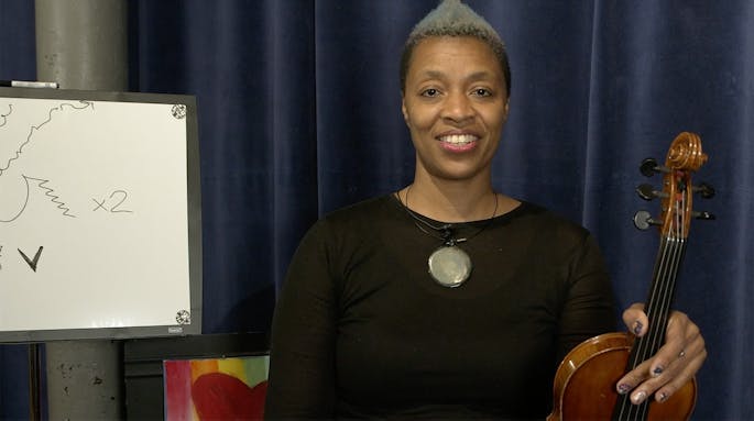 Mazz speaks while holding her violin.