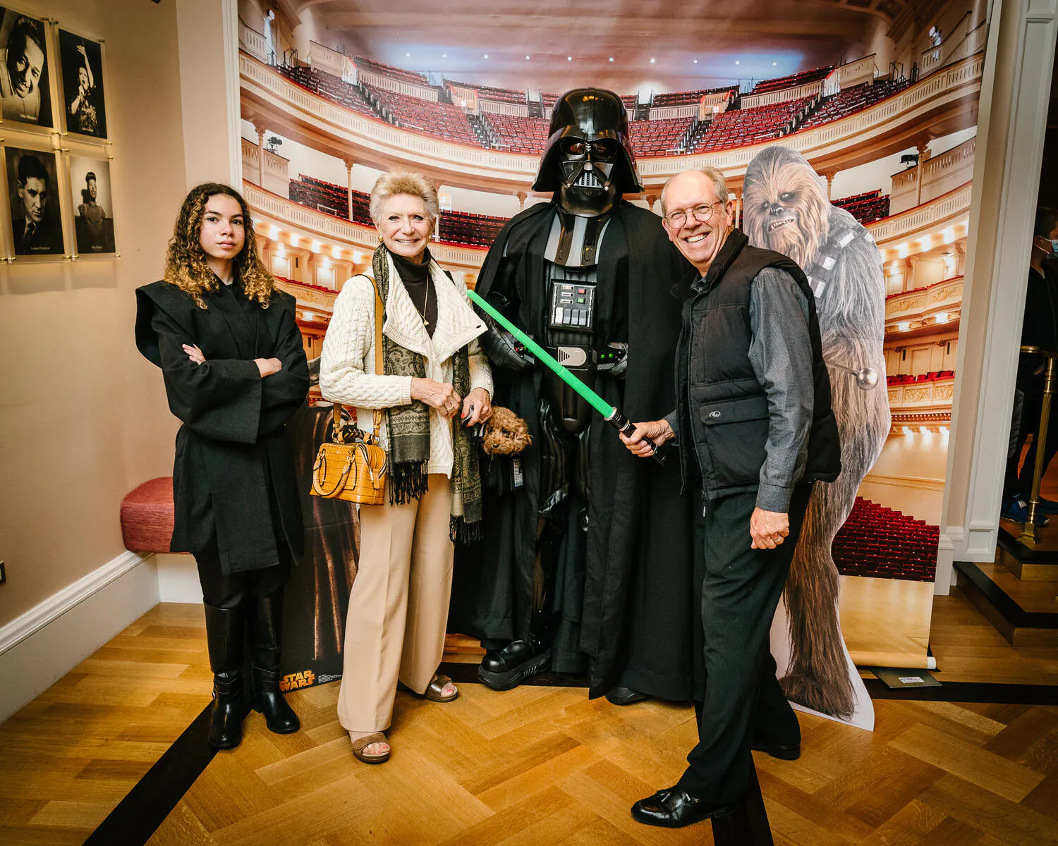 A couple pose in front of a Carnegie Hall backdrop with Star Wars characters beside them.