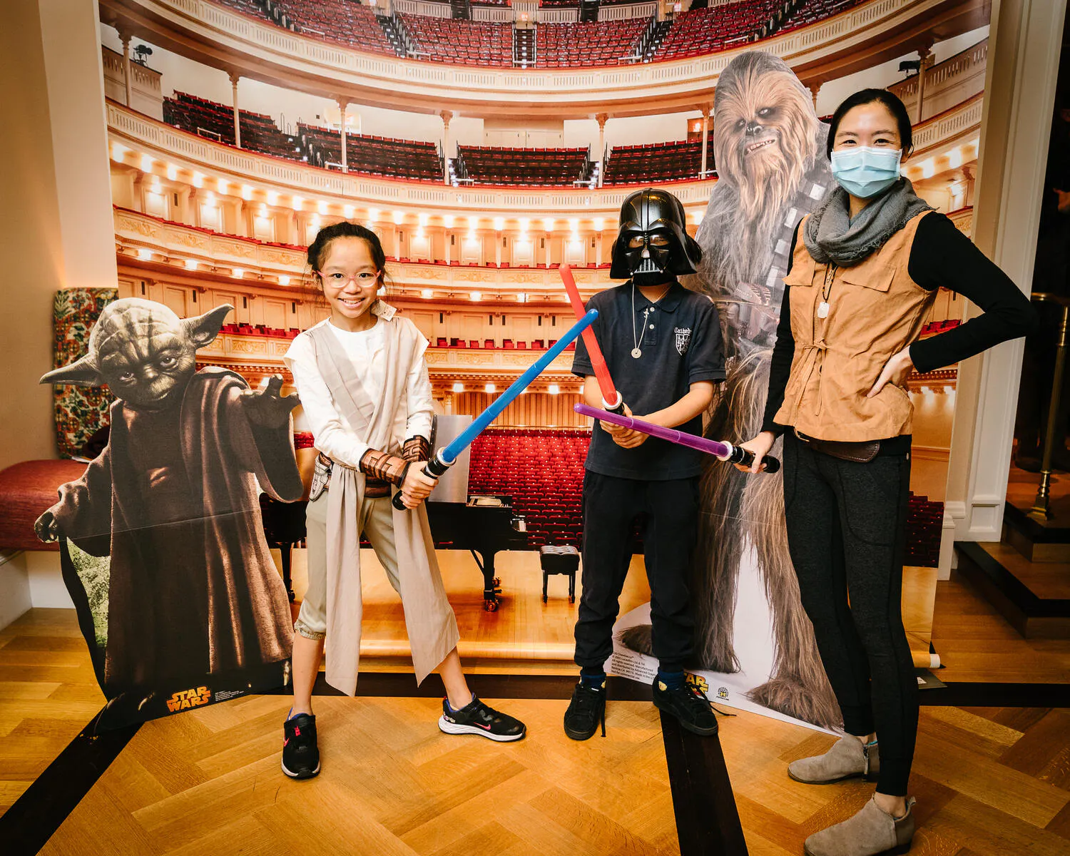 A family poses in Star Wars costumes in front of a Carnegie Hall backdrop.