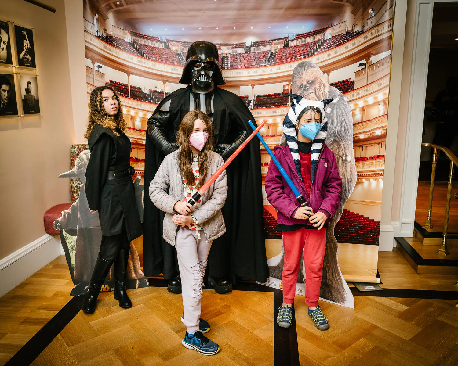 Children pose with Star Wars characters against a backdrop of Carnegie Hall.