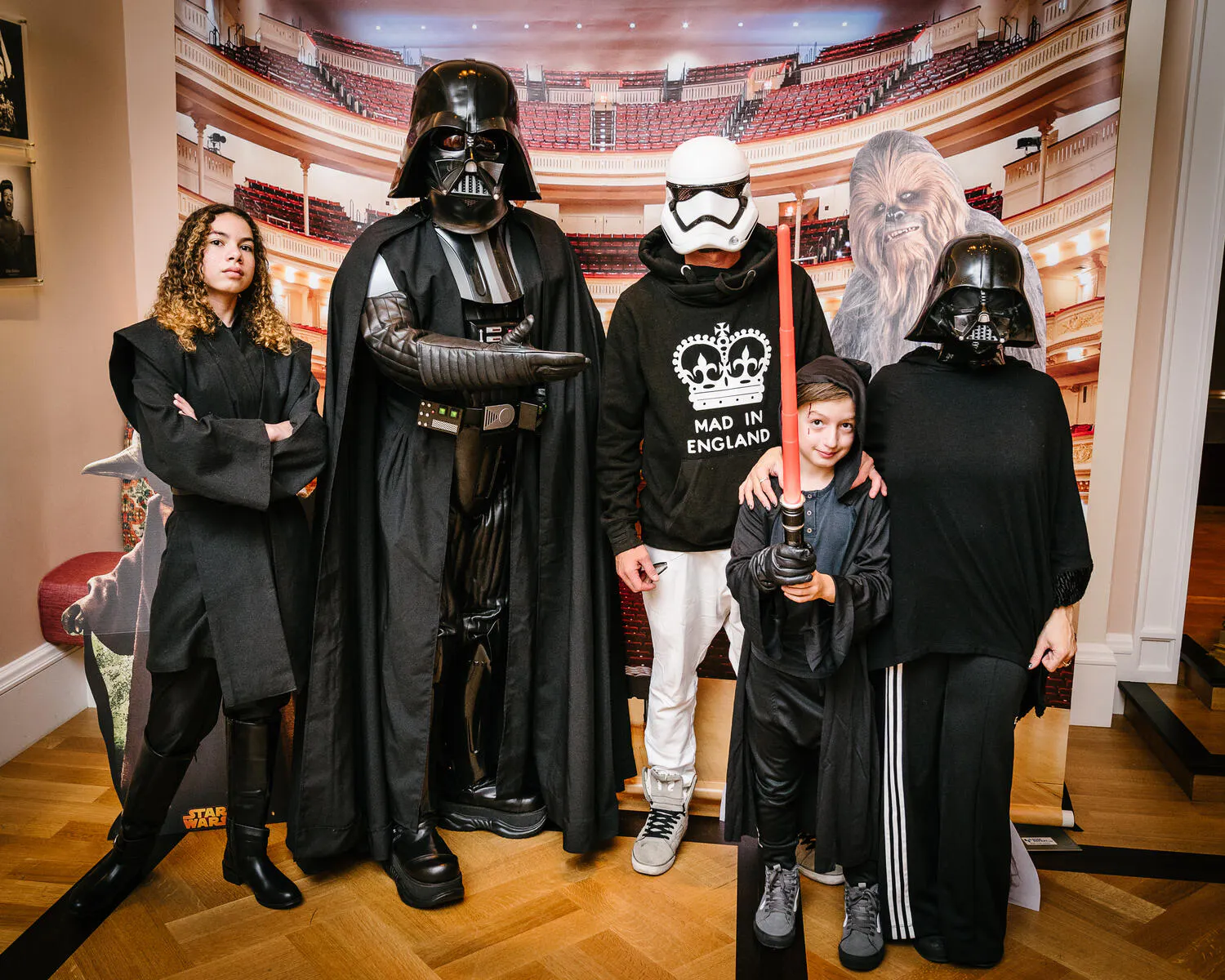 A family dressed in Star Wars costumes pose together in front of a Carnegie hall backdrop.