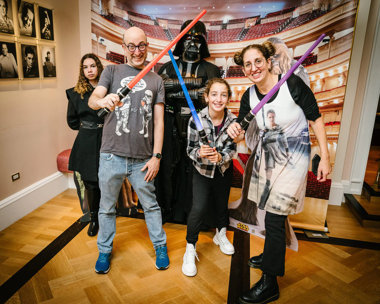 A family dressed in Star Wars costumes pose together in front of a Carnegie hall backdrop.
