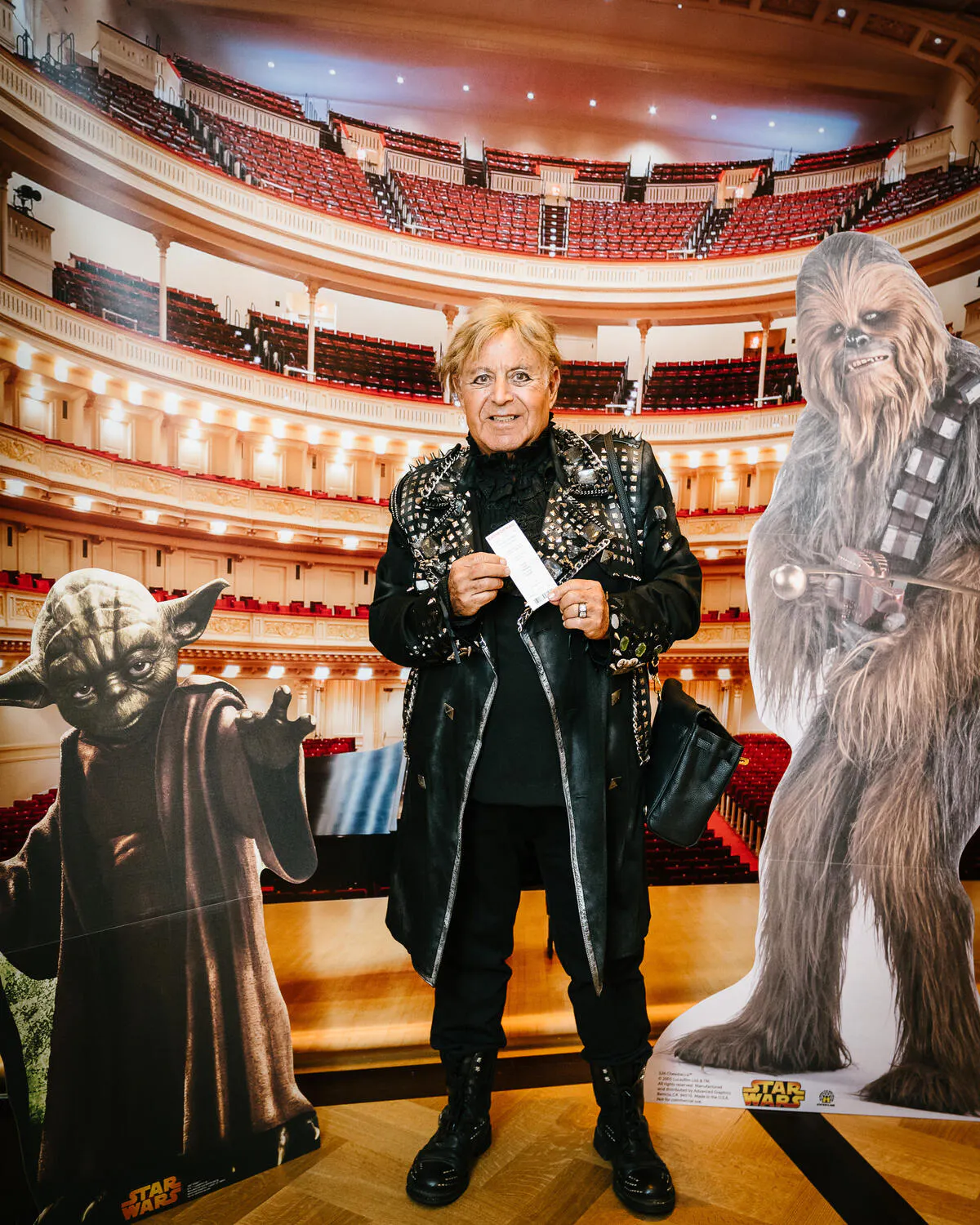 A person posing against a backdrop of Carnegie Hall with Star Wars characters beside them.