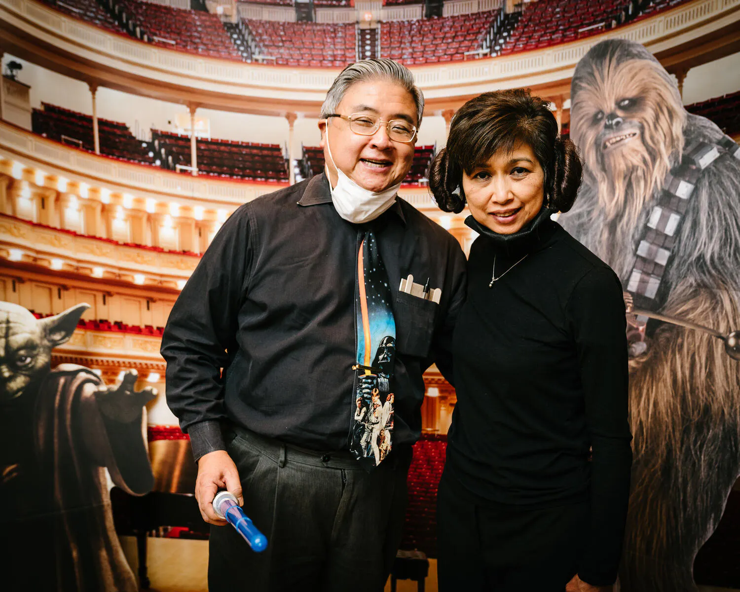 People posing in front of a Carnegie Hall backdrop with Star Wars characters beside them.