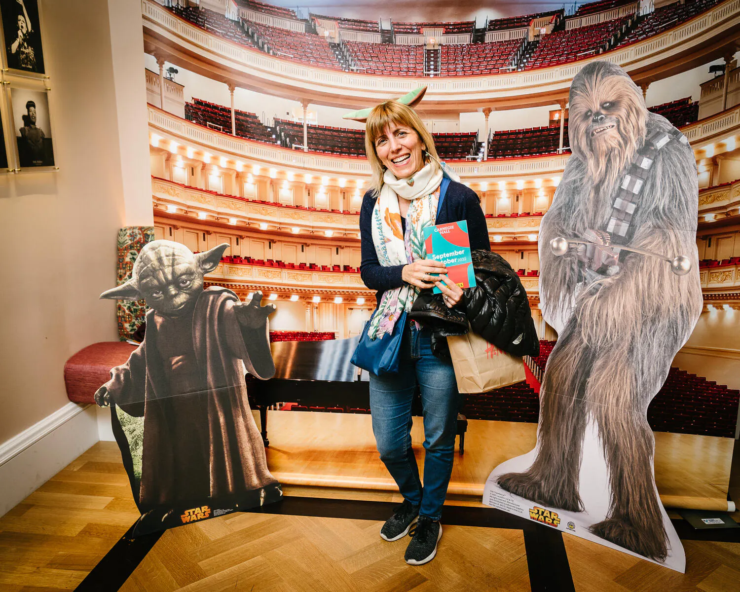 A person posing against a backdrop of Carnegie Hall with Star Wars characters beside them.